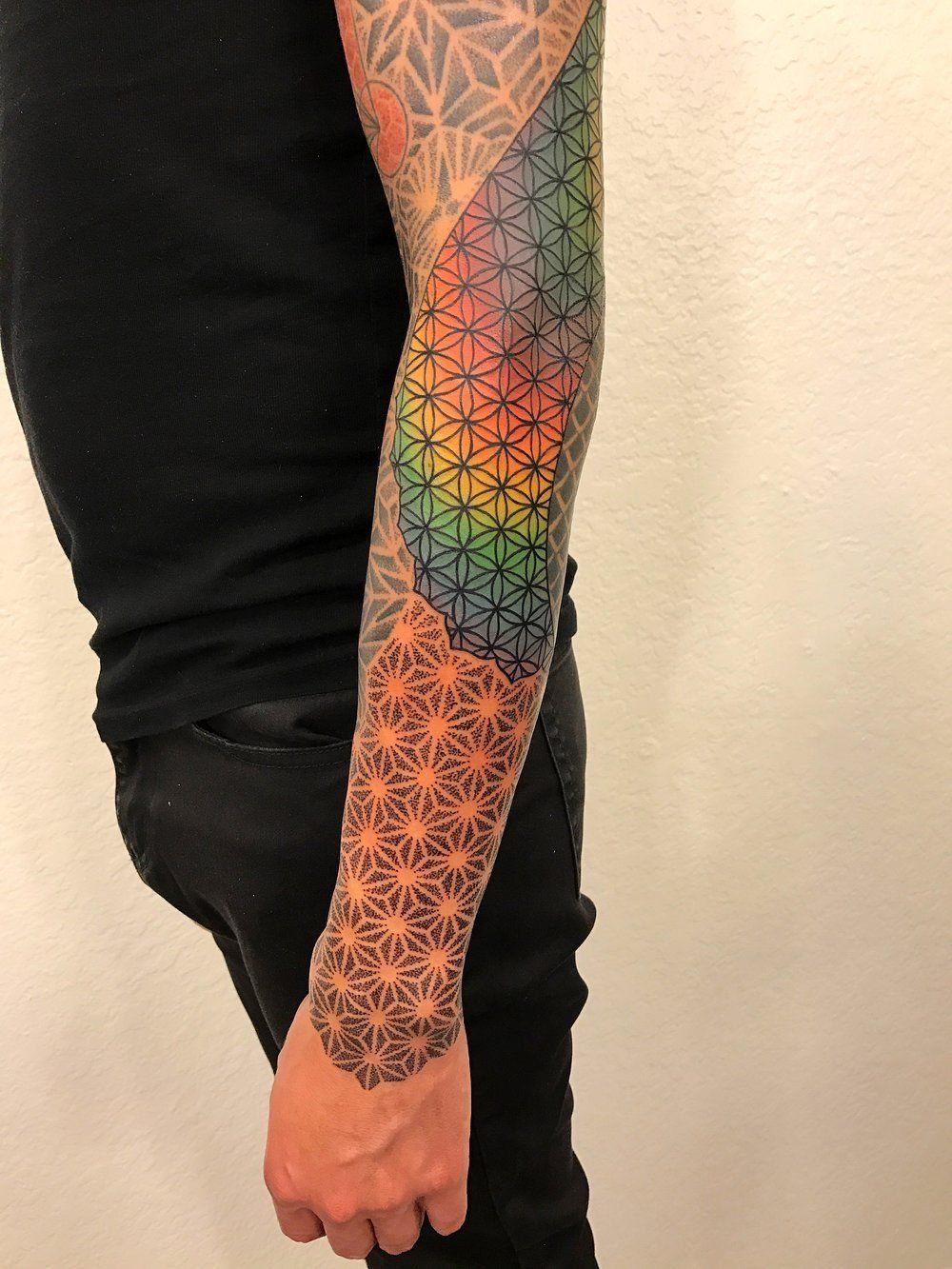 8 Color Tattoo Ideas for Men: Comic, Dragon & Watercolor 8 A man's arm displaying a colorful geometric pattern sleeve tattoo with rainbow gradients.
