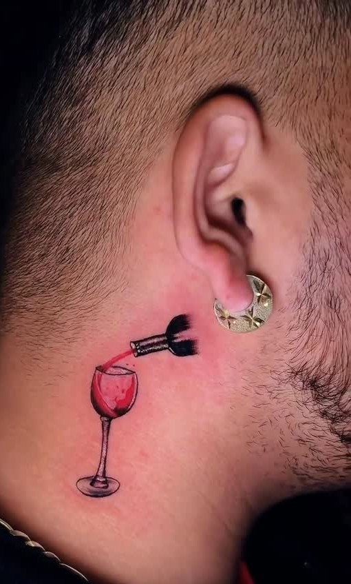 8 Color Tattoo Ideas for Men: Comic, Dragon & Watercolor 7 A small colorful tattoo of a wine glass on a man's neck below his ear.