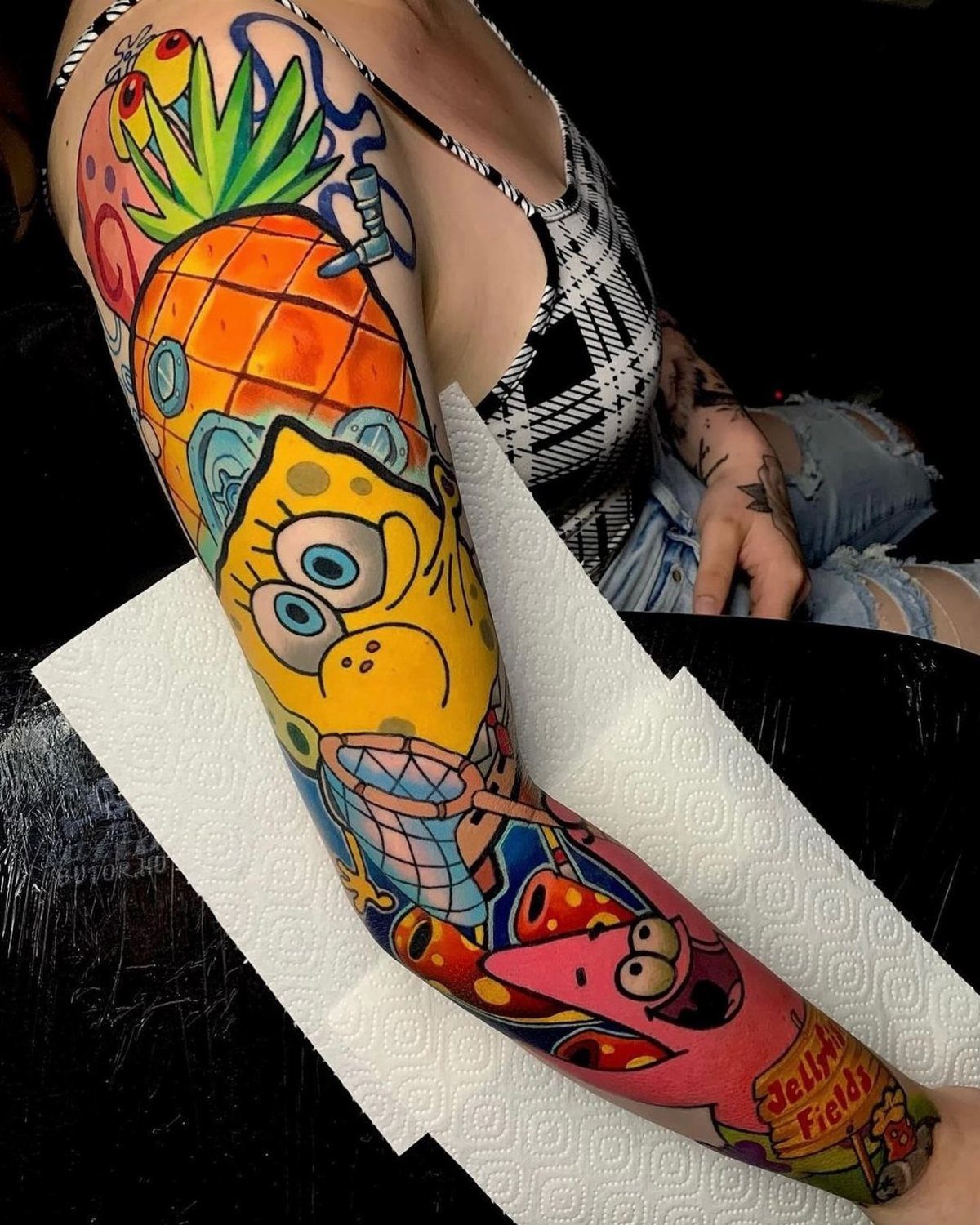 SpongeBob SquarePants and Patrick Star colorful cartoon sleeve tattoo on a person's arm.