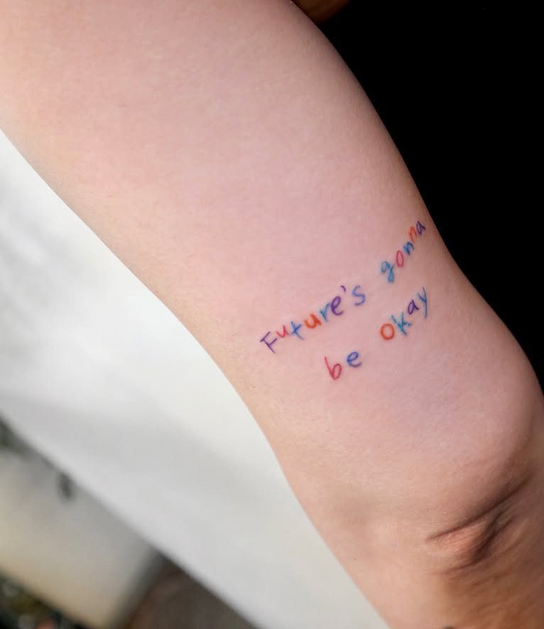 A colorful text tattoo on a person's leg reading Future's gonna be okay.
