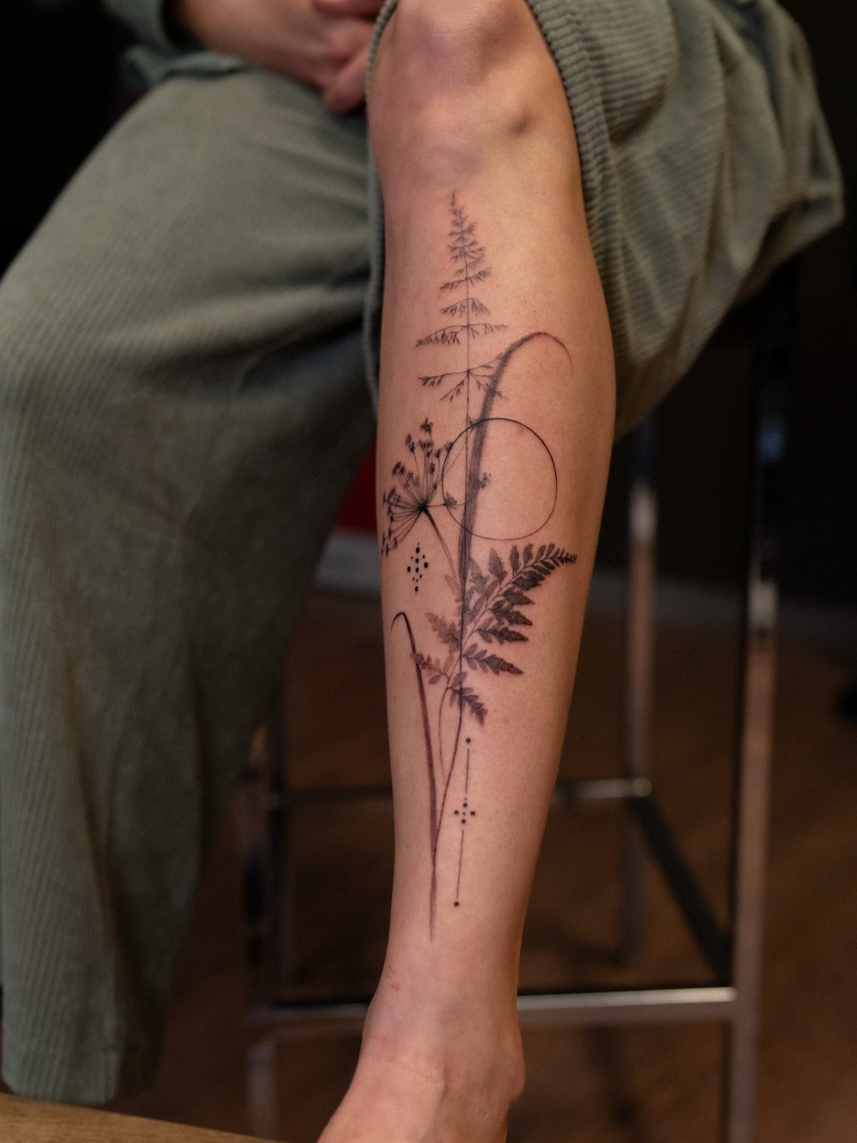 8 Dainty Timeless Tattoos for Minimal Ink That Lasts 7 A fine line botanical tattoo featuring ferns and delicate stems on a person's lower leg.