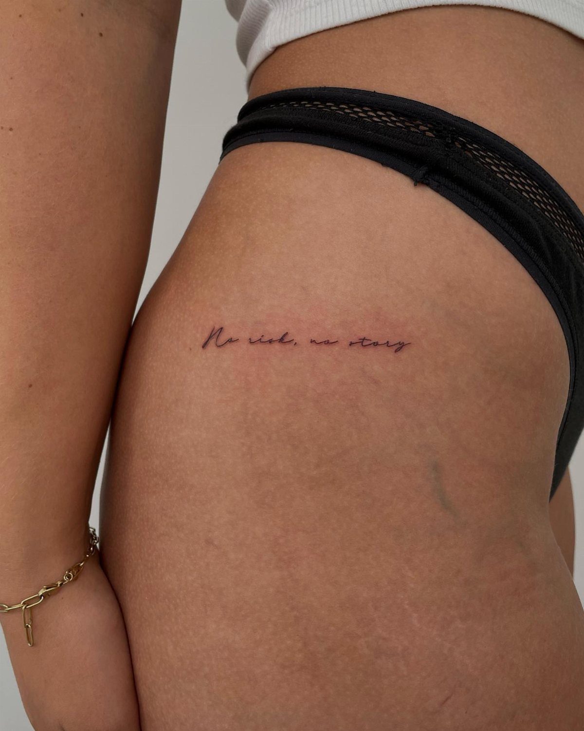 8 Dainty Timeless Tattoos for Minimal Ink That Lasts 5 Fine-line cursive text tattoo reading 'No risk, no story' on a person's hip.