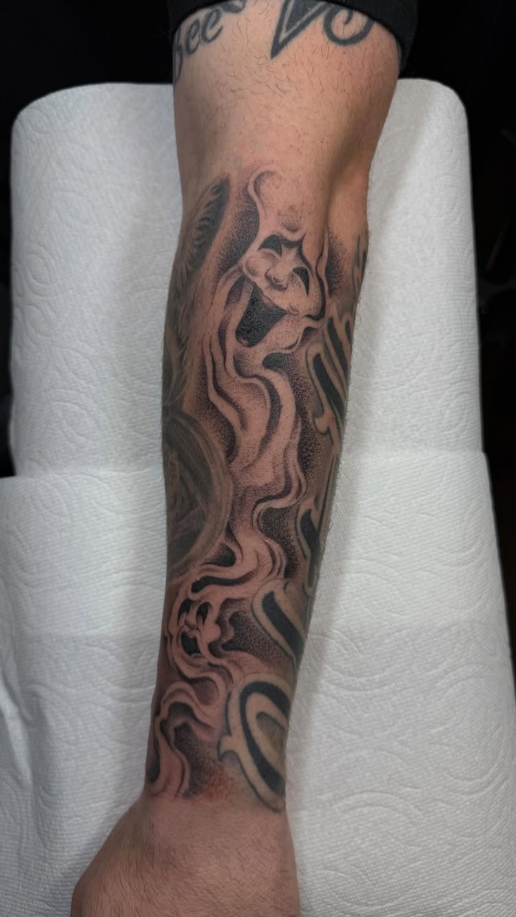 A person's lower leg featuring a large black and grey smoke pattern tattoo design.