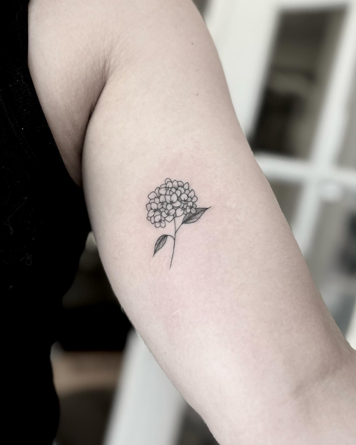 Fine Line Tattoo Aesthetic for Women: 9 Idea Boards 3 A small hydrangea flower fine line tattoo on a person's upper arm.