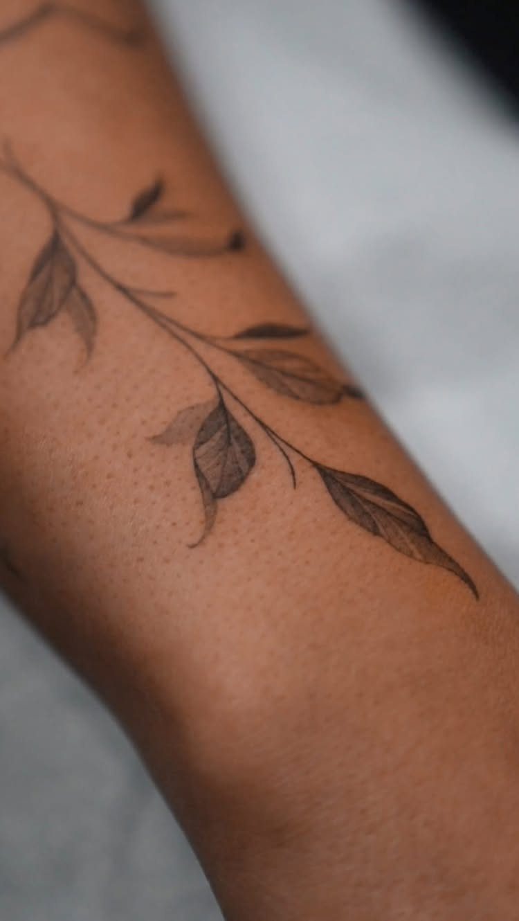 Fine Line Tattoo Aesthetic for Women: 9 Idea Boards 5 A fine line tattoo of a leafy branch on a person's arm.