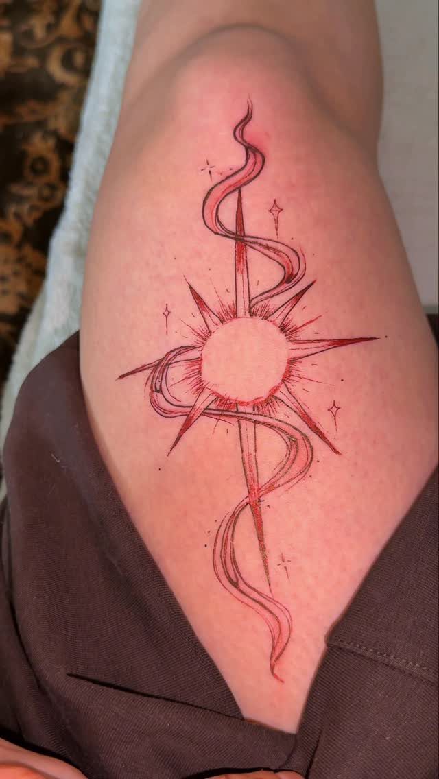 Fine Line Tattoo Aesthetic for Women: 9 Idea Boards 8 A red fine line sun tattoo with wavy lines on a person's leg.
