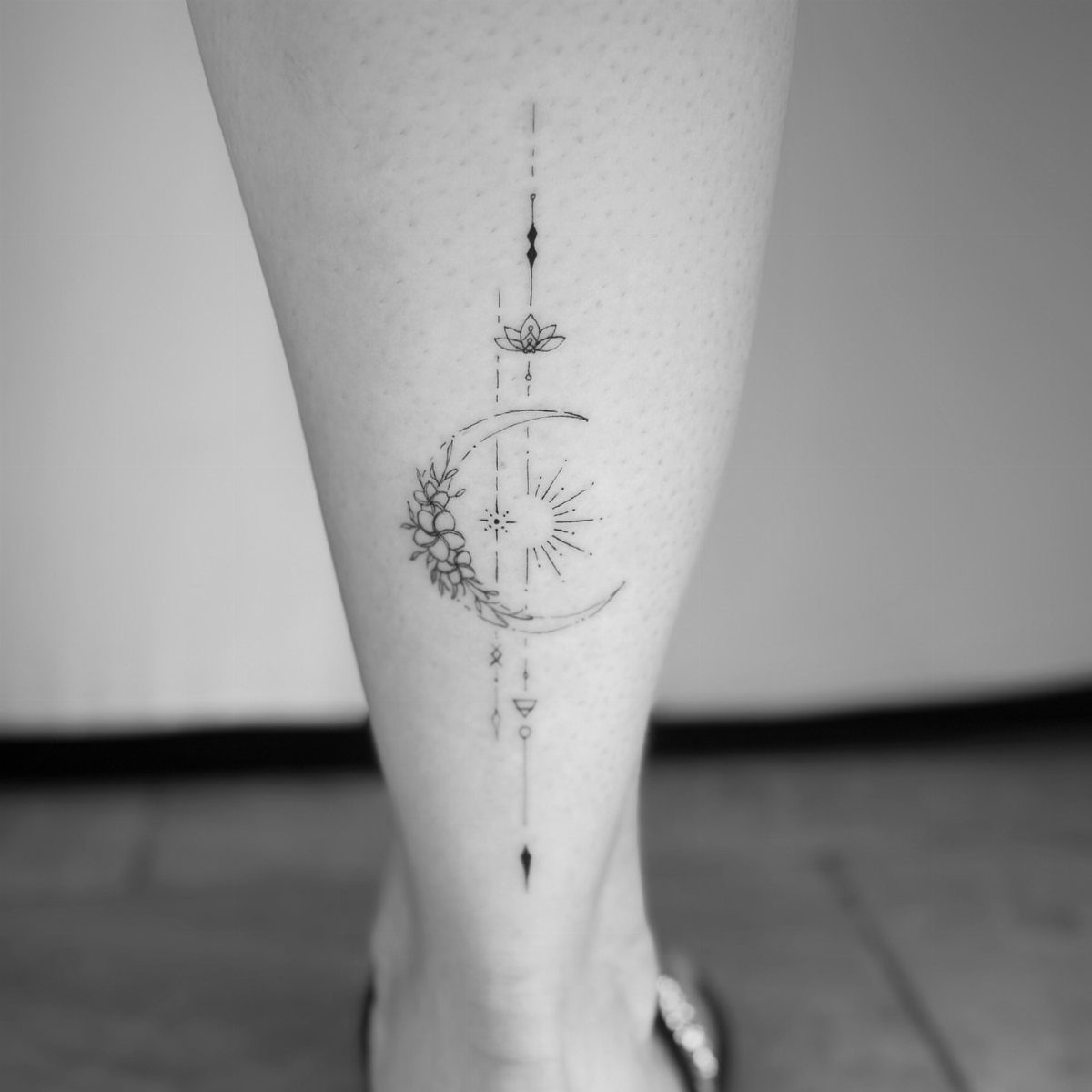 Fine Line Tattoo Aesthetic for Women: 9 Idea Boards 2 A fine line tattoo of a sun and crescent moon on a person's leg.