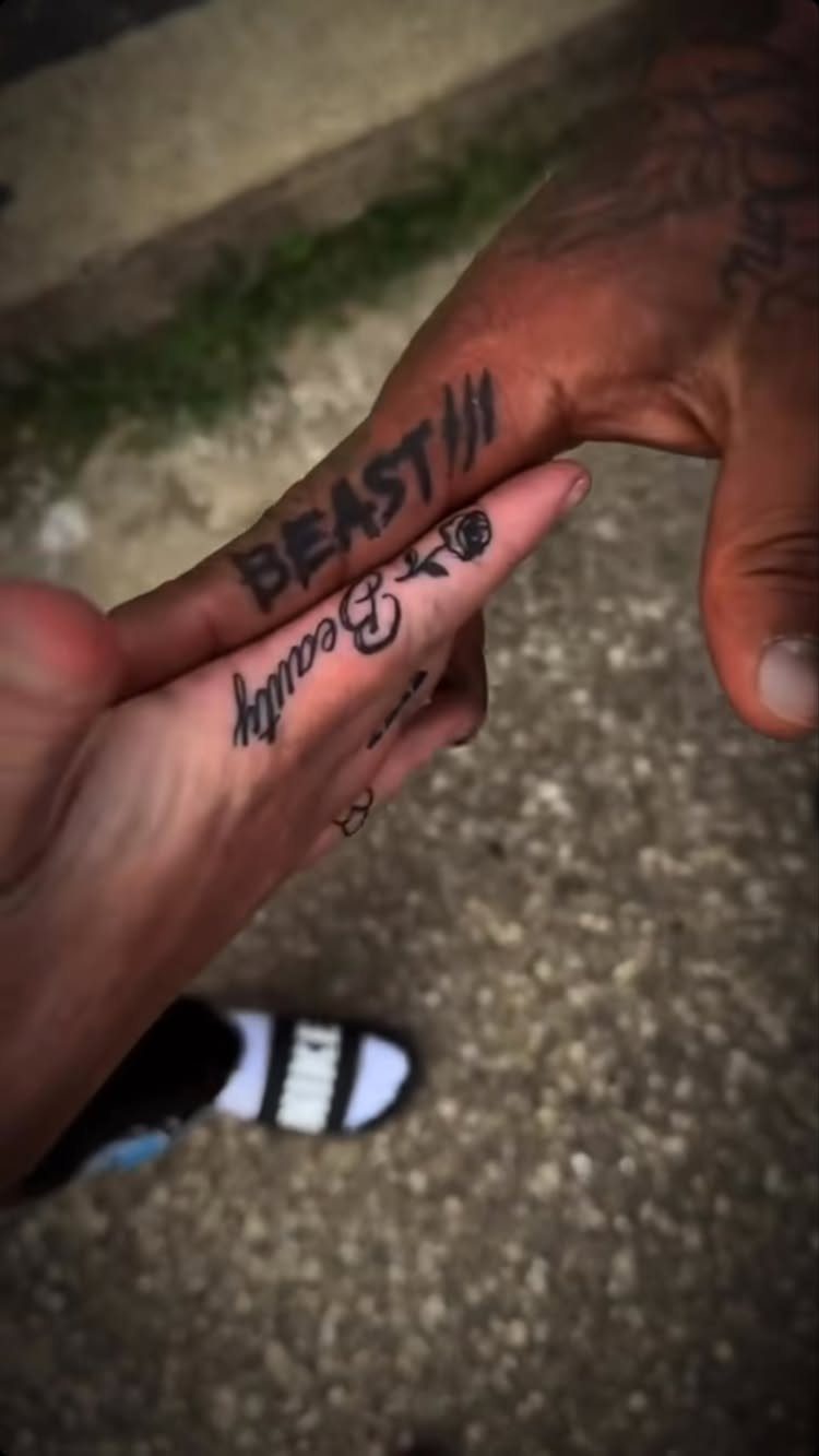 Two hands held together showing matching Beast and Beauty finger tattoos.