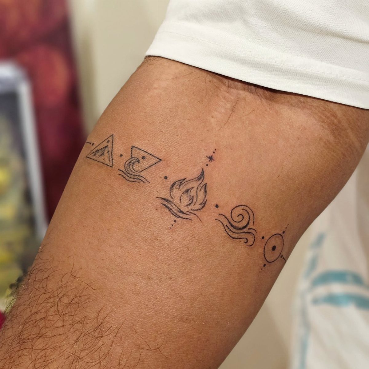 Five Elements Tattoo and 5 Symbol Arrangements to Try 5 Five minimalist black ink elemental symbols tattooed in a horizontal line on a person's arm.