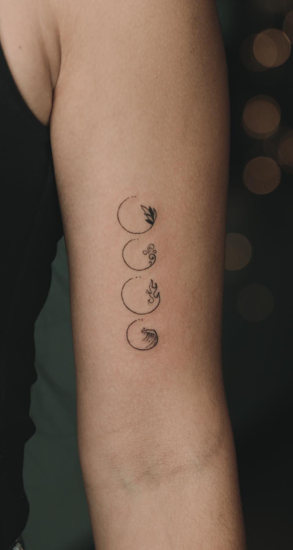 Five Elements Tattoo and 5 Symbol Arrangements to Try 2 Four small black ink elemental tattoos arranged vertically on a person's upper arm.