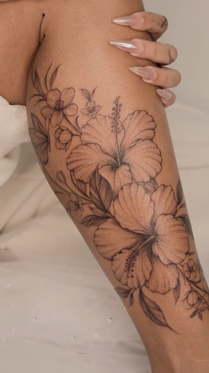 Large black and grey hibiscus flower tattoo covering a person's leg with detailed petals.
