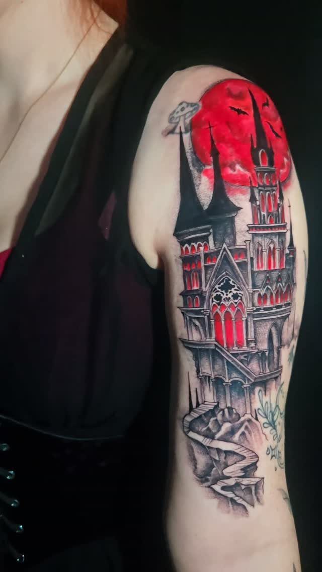A detailed gothic castle tattoo on an arm featuring spires and a large red moon background.