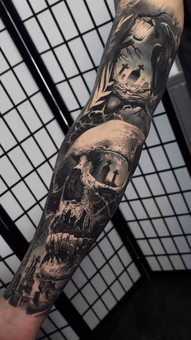 A detailed black and grey gothic skull tattoo covering a person's entire arm.