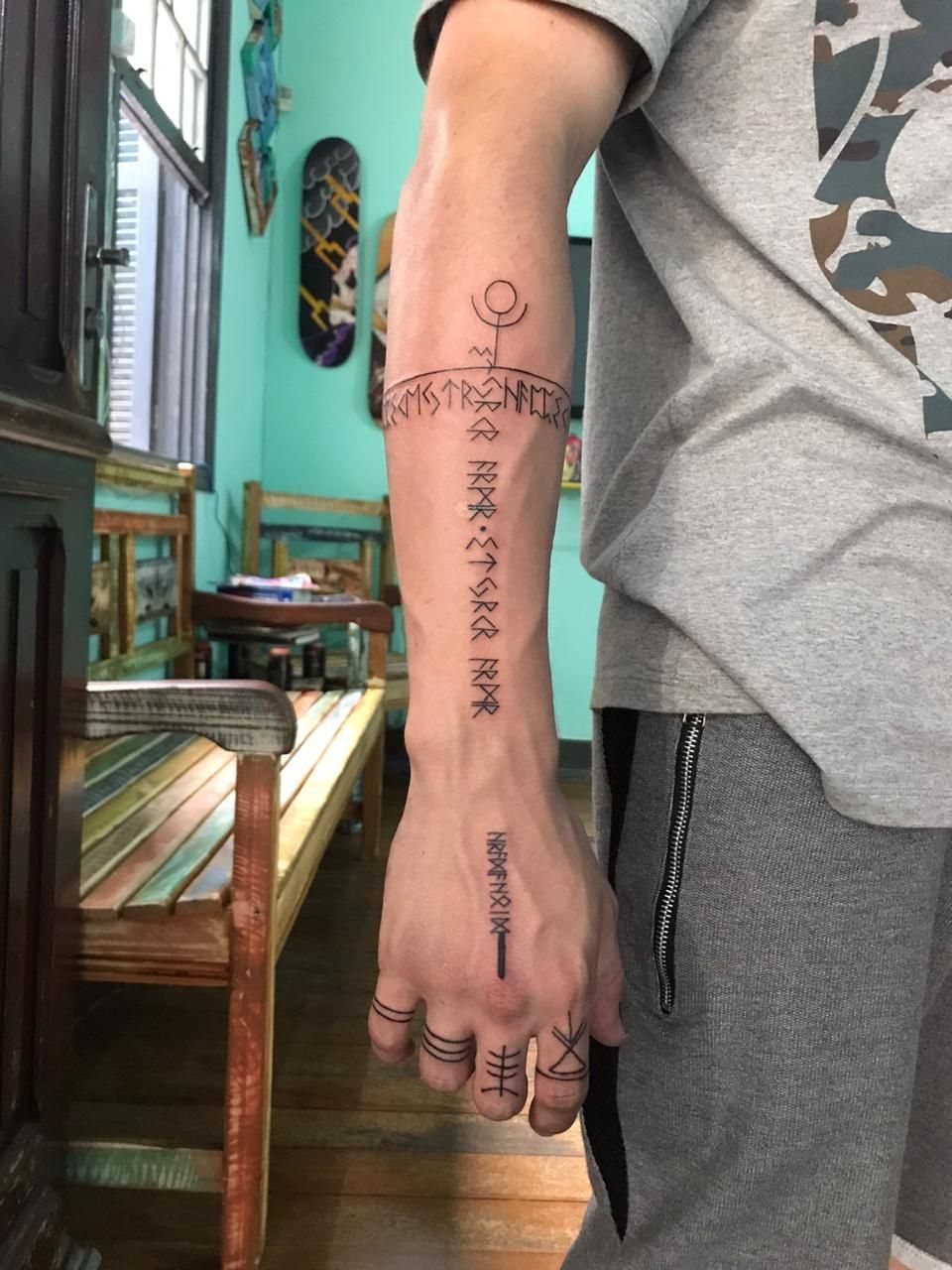 Nordic Runes Tattoo: 10 Design Ideas Worth Considering 1 A person's arm and hand displaying various black ink Elder Futhark rune tattoos.