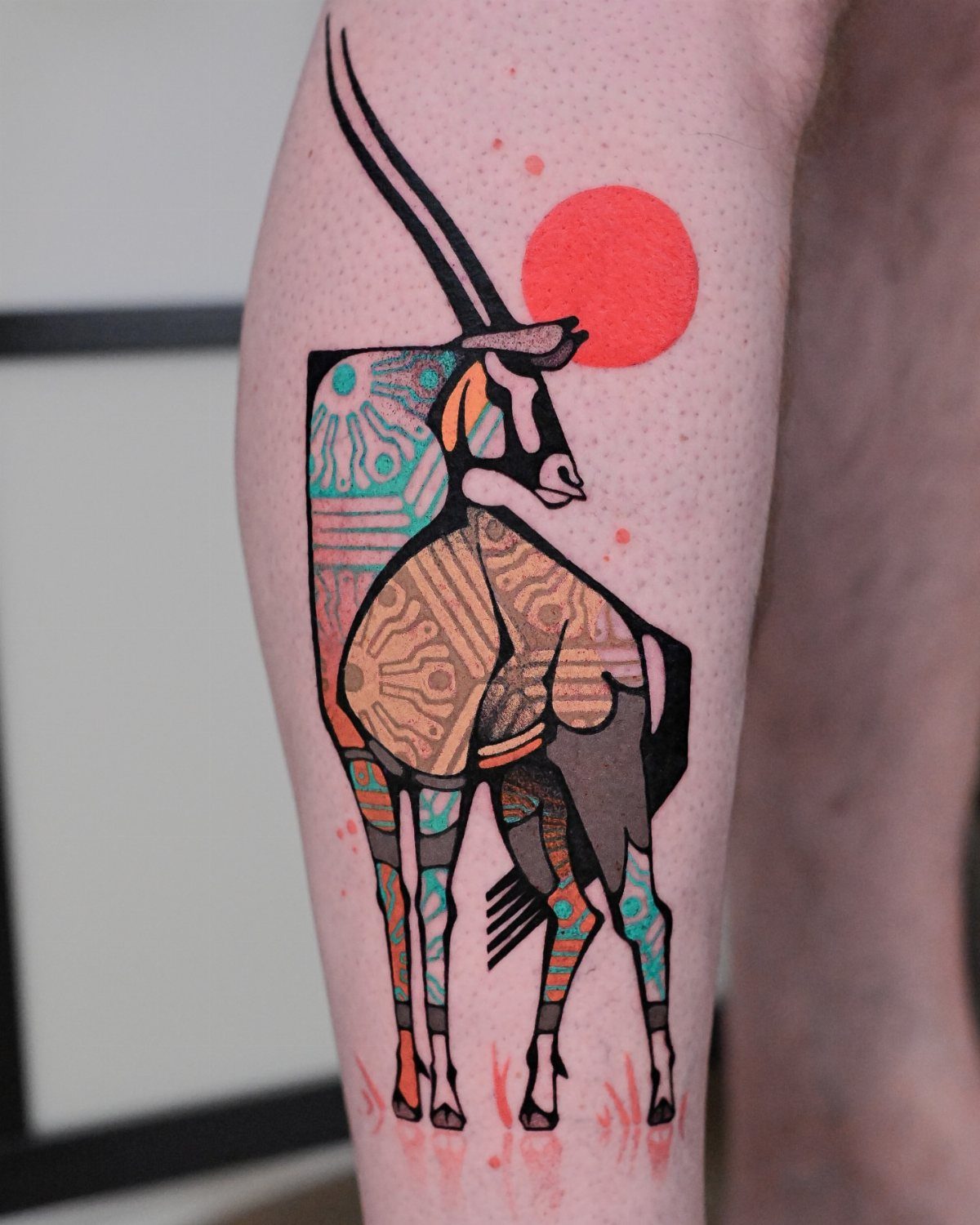 An intricate, colorful animal pattern tattoo of an antelope on a person's leg.