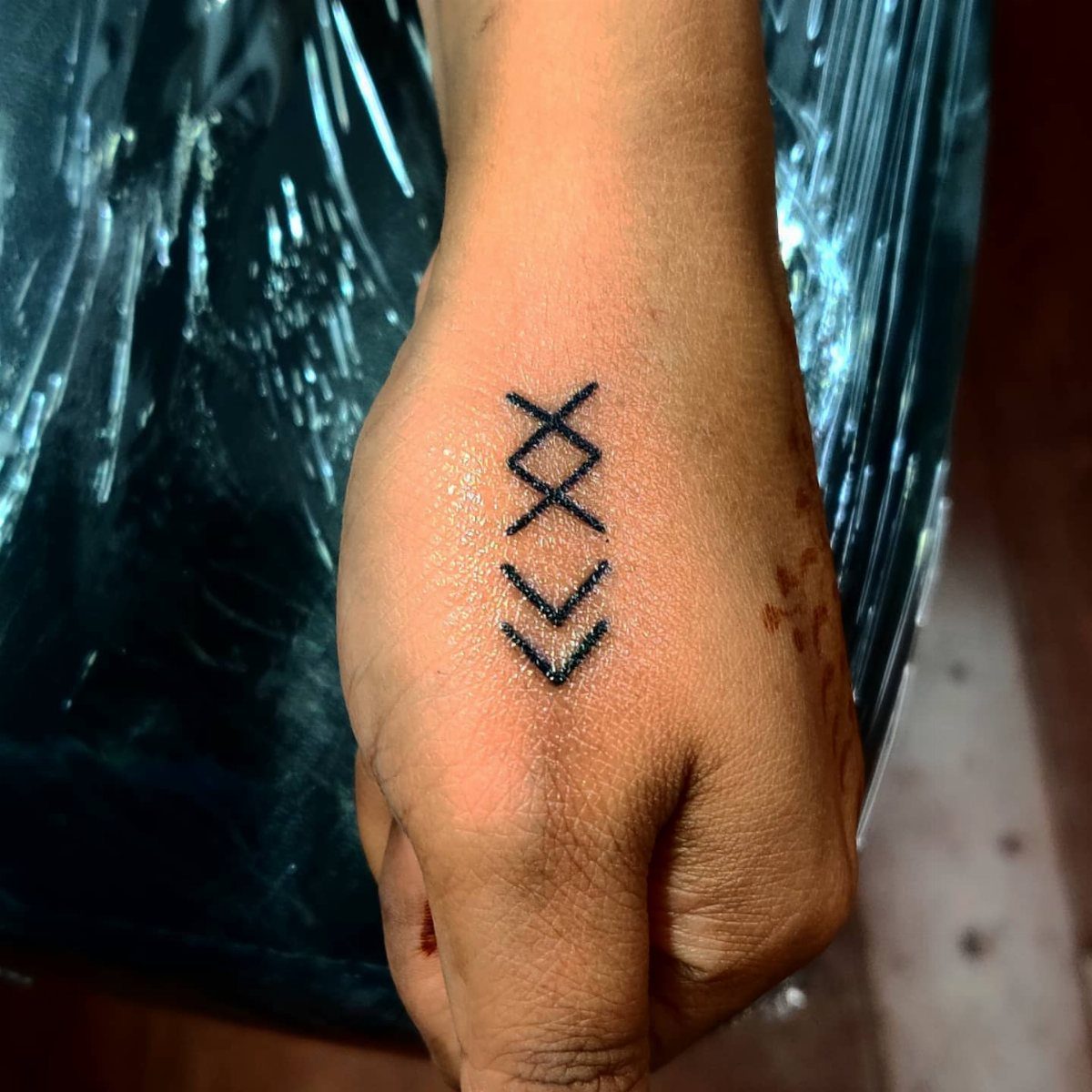 Rune Tattoo Ideas: 18 Symbols and Placements Worth Studying 15 A black ink rune tattoo on the back of a person's hand.