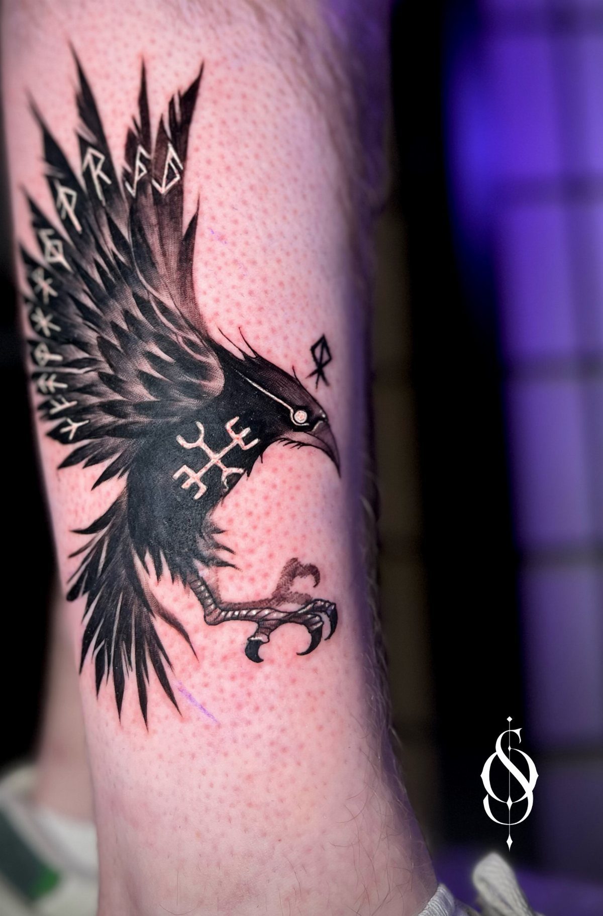 Rune Tattoo Ideas: 18 Symbols and Placements Worth Studying 9 A black ink raven tattoo featuring integrated Norse runes on a person's skin.
