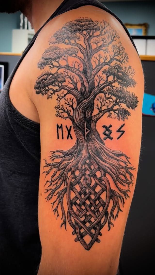 Rune Tattoo Ideas: 18 Symbols and Placements Worth Studying 14 A large black ink tattoo of a tree with intricate roots and Norse runes on a person's arm.