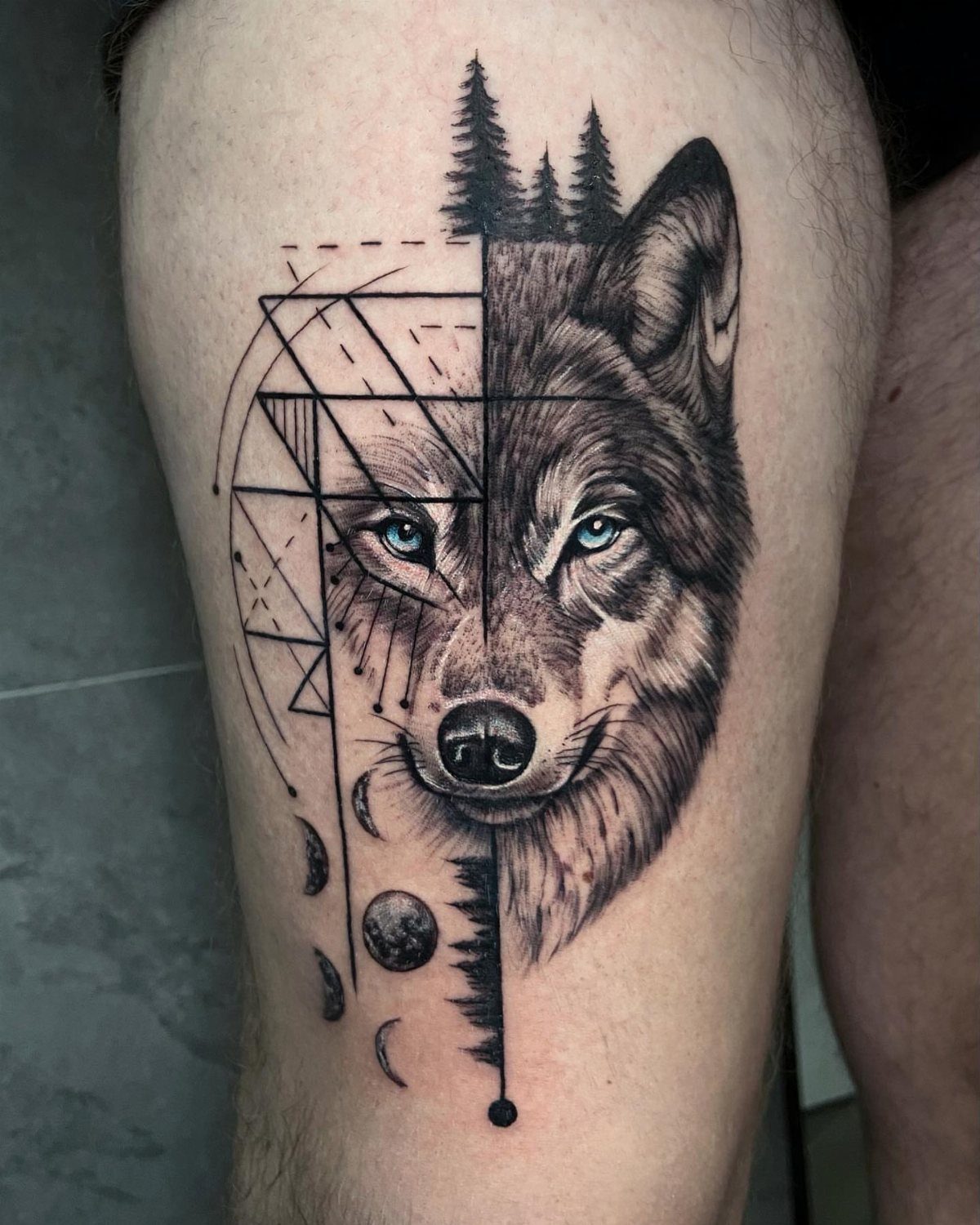 A detailed black and grey wolf tattoo combining realistic fur textures with geometric line art patterns.