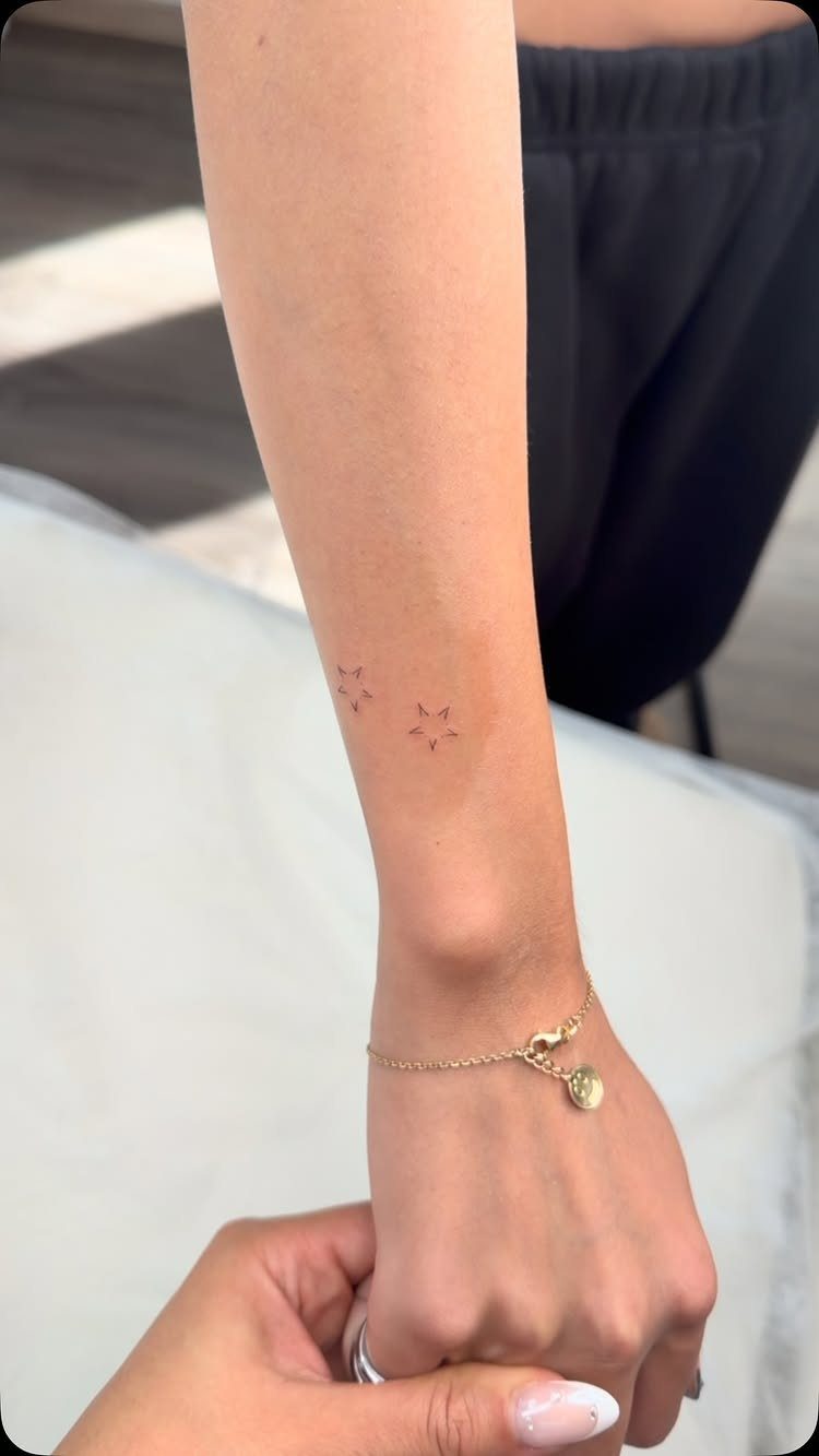 Two tiny red star tattoos on a person's inner forearm near the wrist.