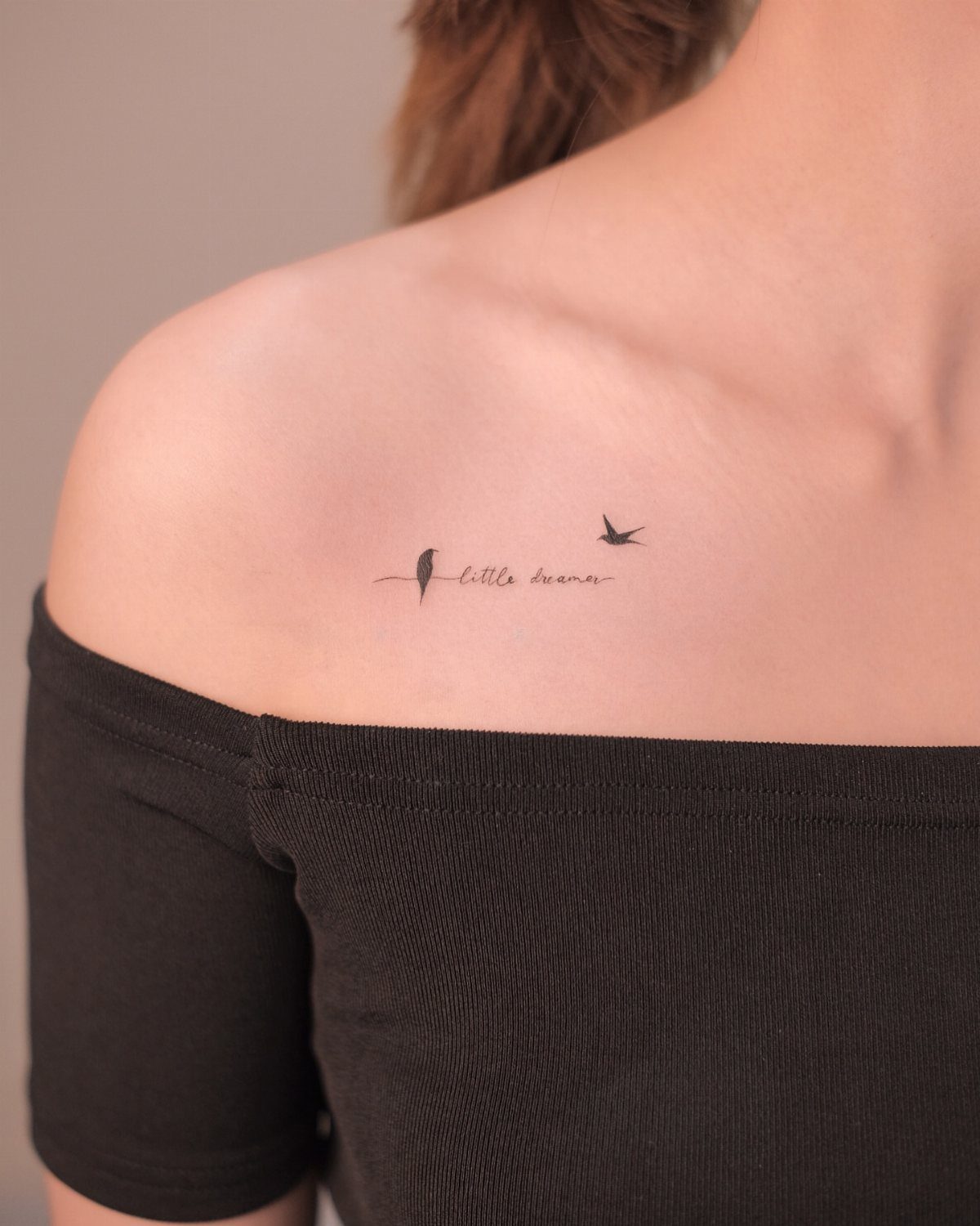 15 Small Tattoo Placement Ideas for Every Style 4 A small bird and cursive text tattoo placed on a person's collarbone.