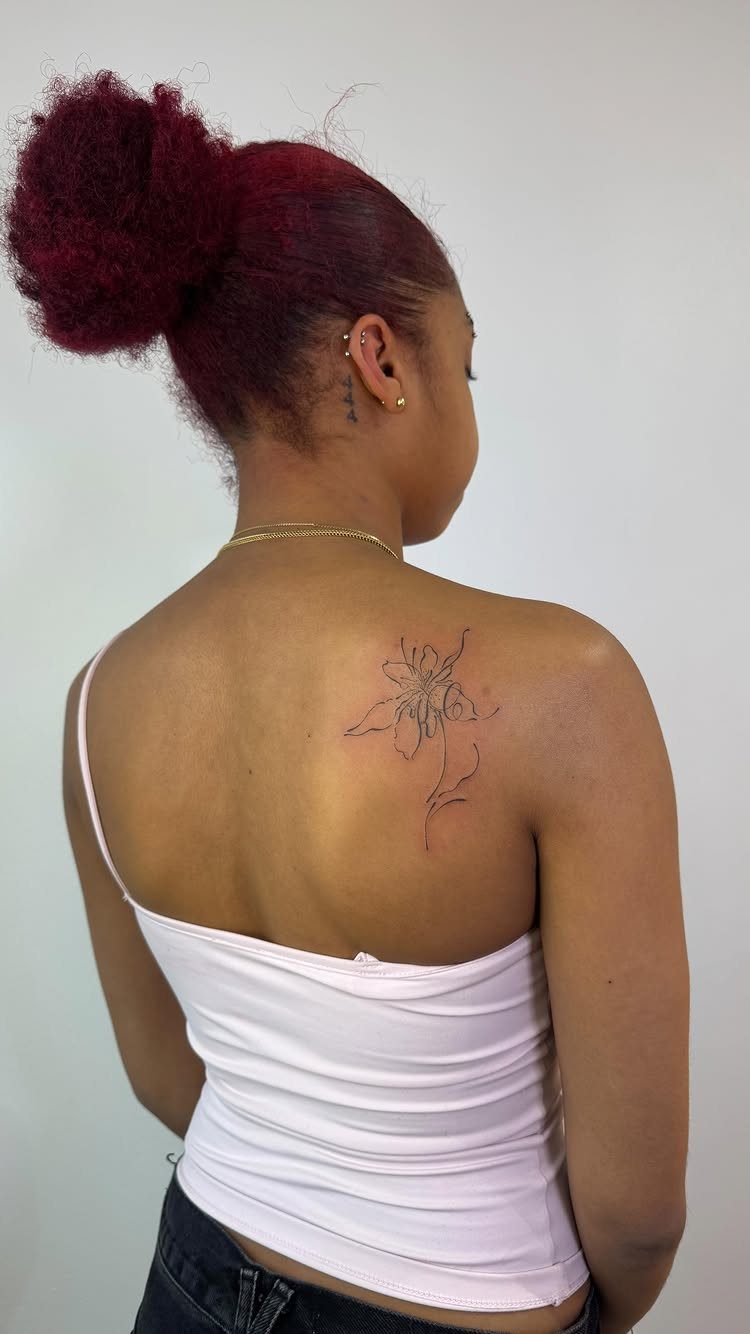 15 Small Tattoo Placement Ideas for Every Style 5 A woman with red hair showing a delicate floral tattoo on her right shoulder blade.