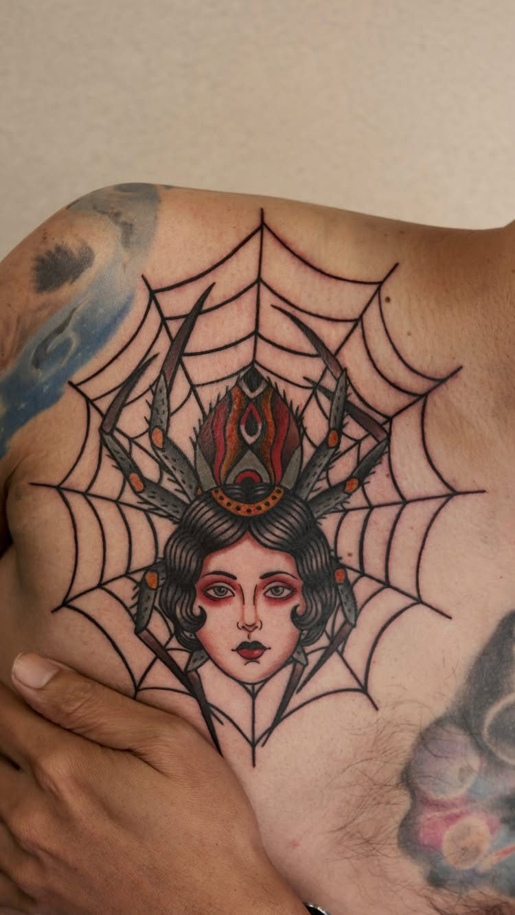 Traditional spider lady tattoo with a woman's face inside a large spider web on skin.