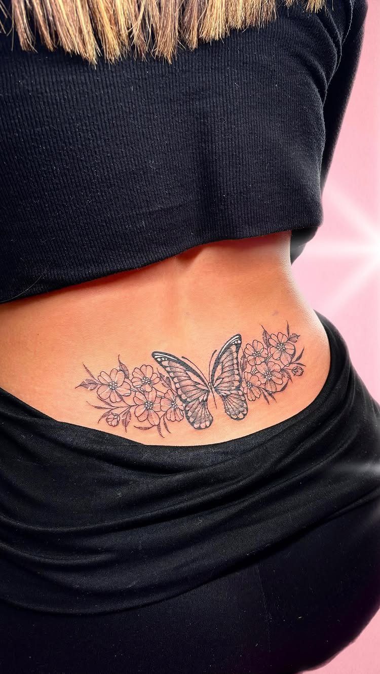 A butterfly and floral tattoo located on a person's lower back skin.