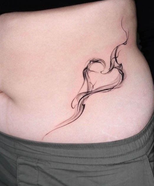 A smoke-style heart tattoo placed on a person's hip and lower abdomen.