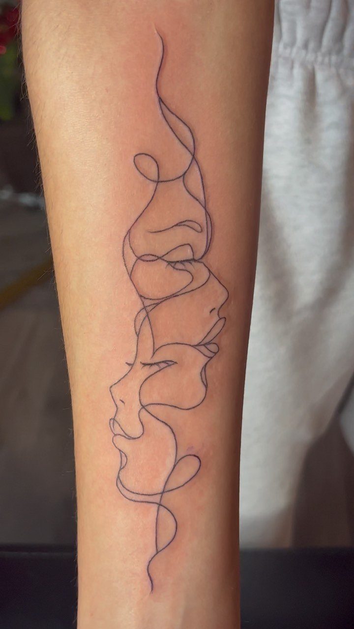 A single line tattoo of abstract facial profiles on a person's forearm.