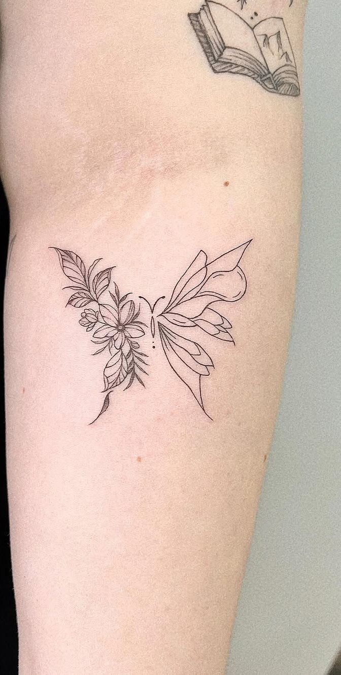 14 Tattoo Style Outline Ideas for Your Next Appointment 1 A fine line butterfly tattoo with floral patterns on a person's arm.