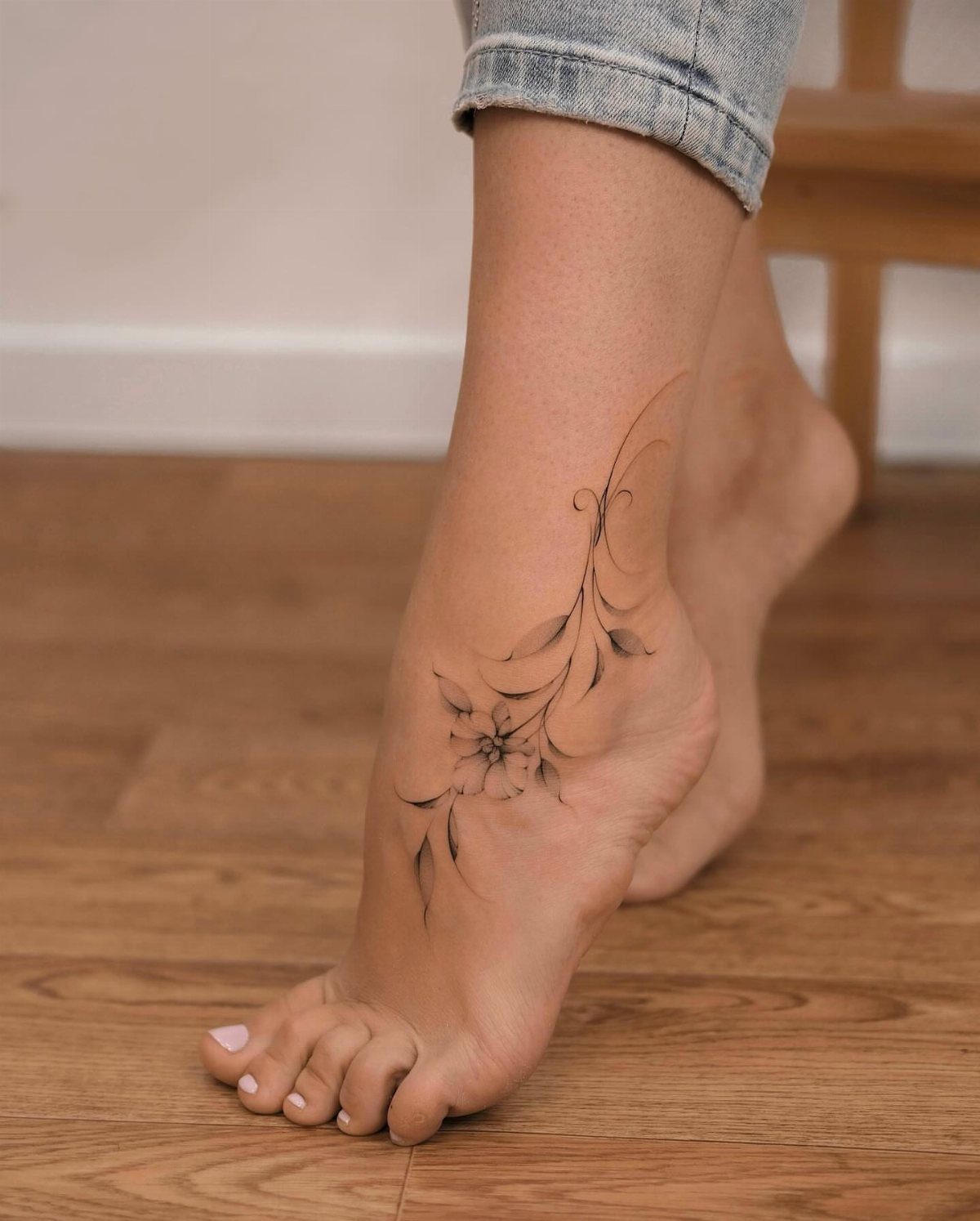 14 Tattoo Style Outline Ideas for Your Next Appointment 9 A person's foot and ankle decorated with a delicate black ink floral line art tattoo.