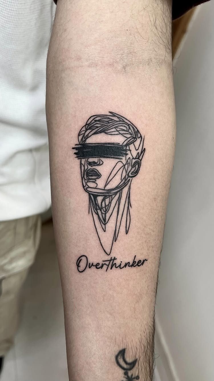 14 Tattoo Style Outline Ideas for Your Next Appointment 14 A fine line black ink tattoo of a face and the word Overthinker on an arm.