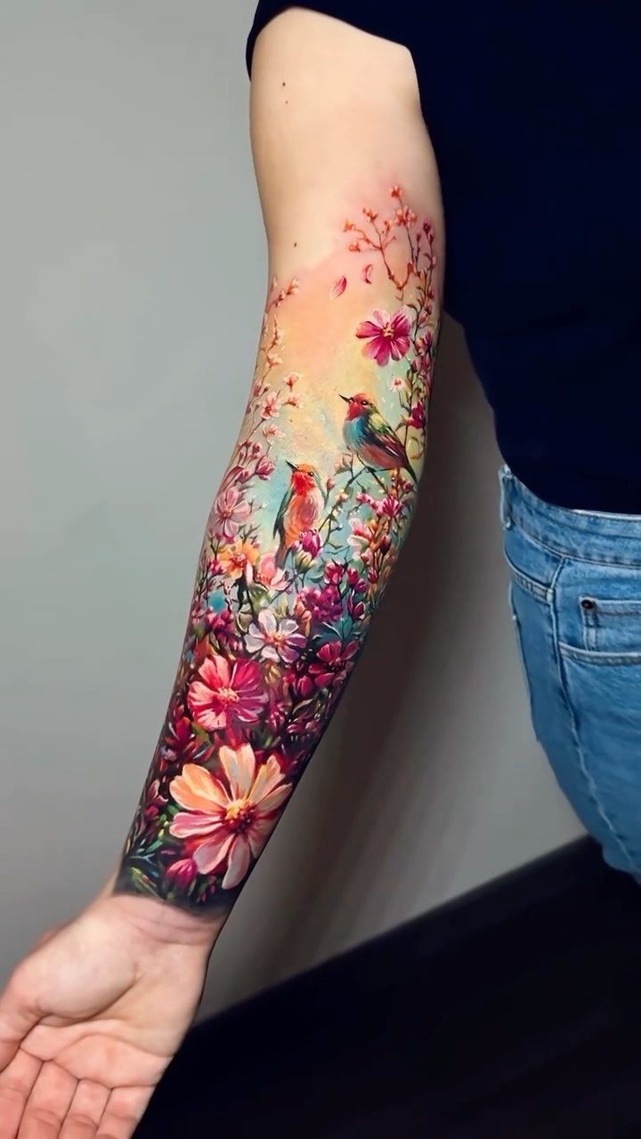 A colorful realistic sleeve tattoo of birds and flowers on a person's forearm.