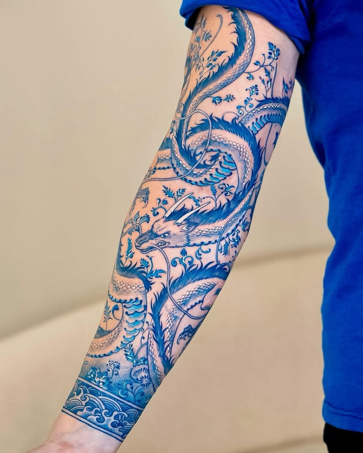 Traditional Dragon Tattoo: 9 Bold Designs That Carry Real Weight 7 A detailed blue dragon tattoo winding around a person's forearm with intricate scale patterns.