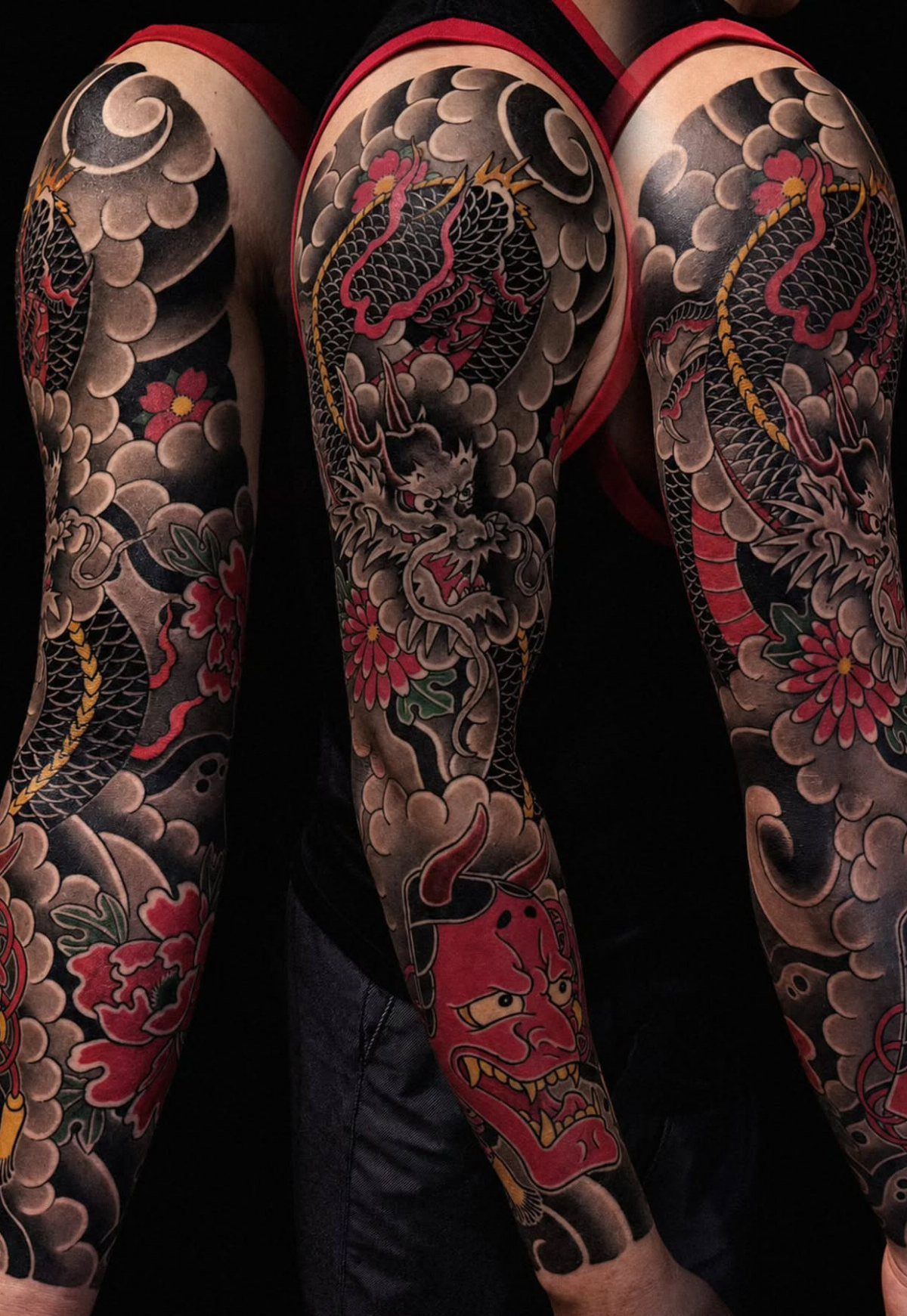 Traditional Dragon Tattoo: 9 Bold Designs That Carry Real Weight 2 Tattooed arms featuring a large Japanese dragon design with red flowers and a demon mask.