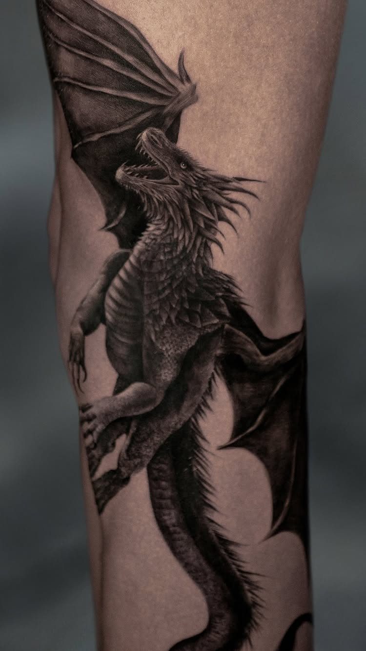 Traditional Dragon Tattoo: 9 Bold Designs That Carry Real Weight 1 A detailed black and grey Western dragon tattoo covering a person's leg.
