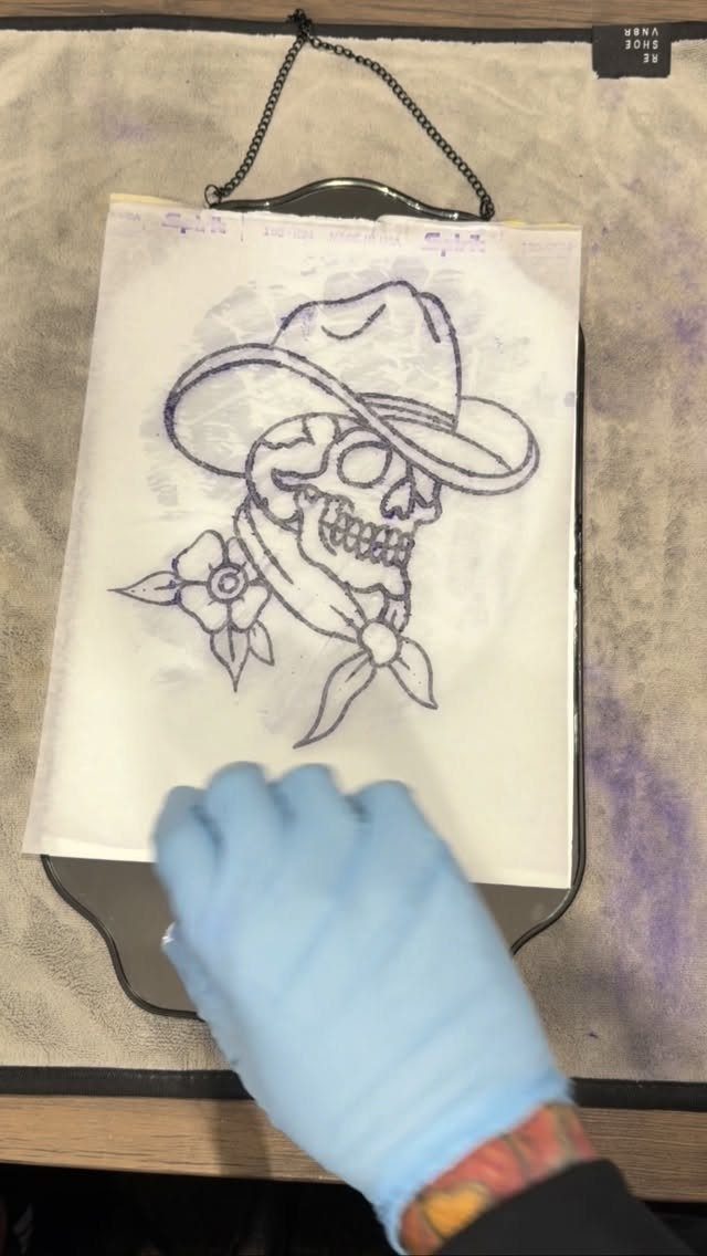 A skull wearing a cowboy hat and bandana drawn in ink on white paper.