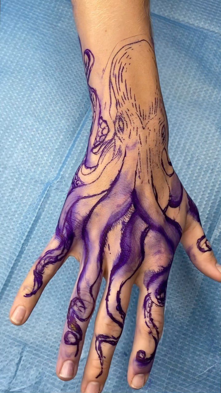 Purple ink octopus stencil design drawn onto a person's hand and wrist.
