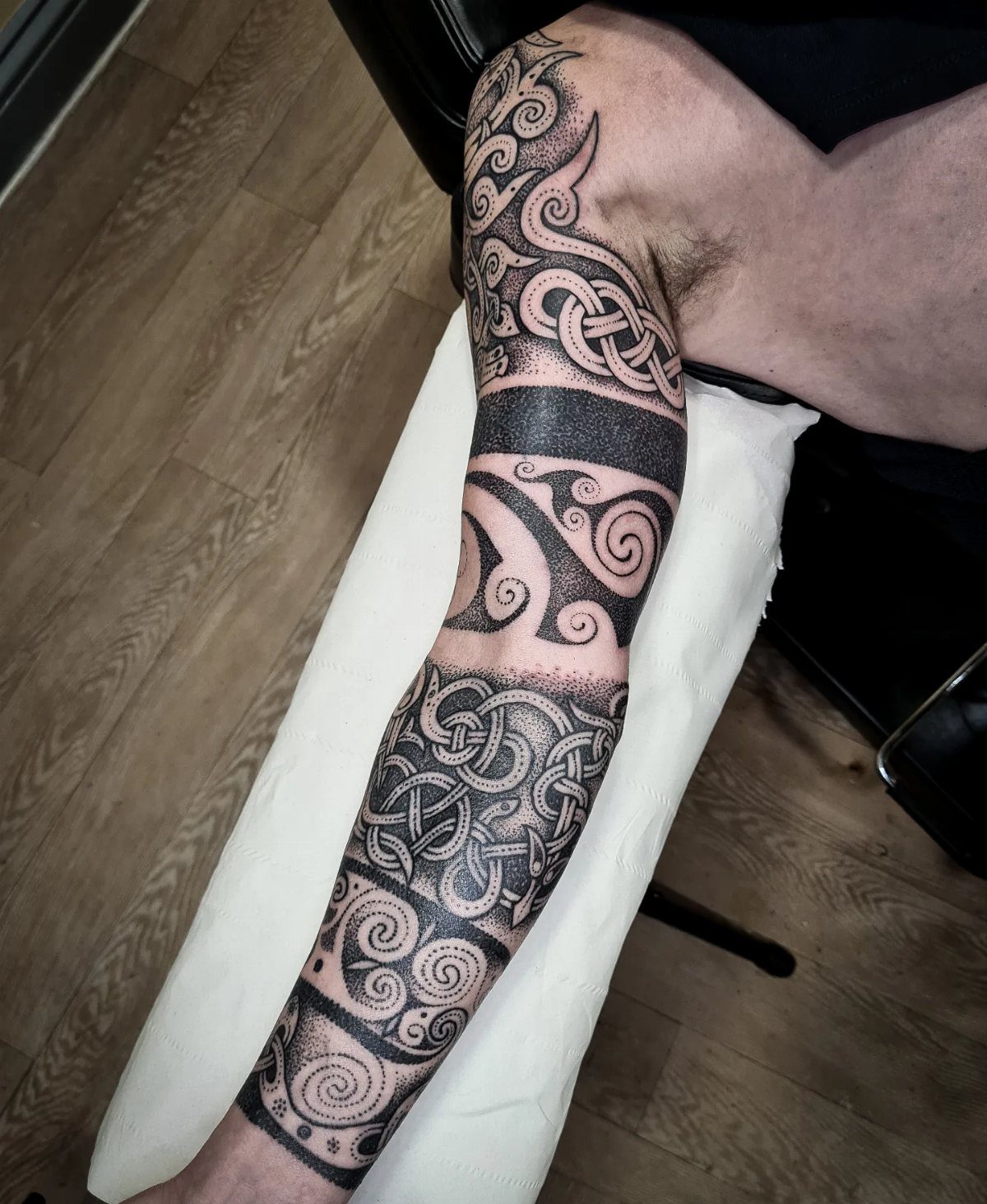 A leg featuring a large black ink tattoo with intricate Celtic knotwork and swirling patterns.