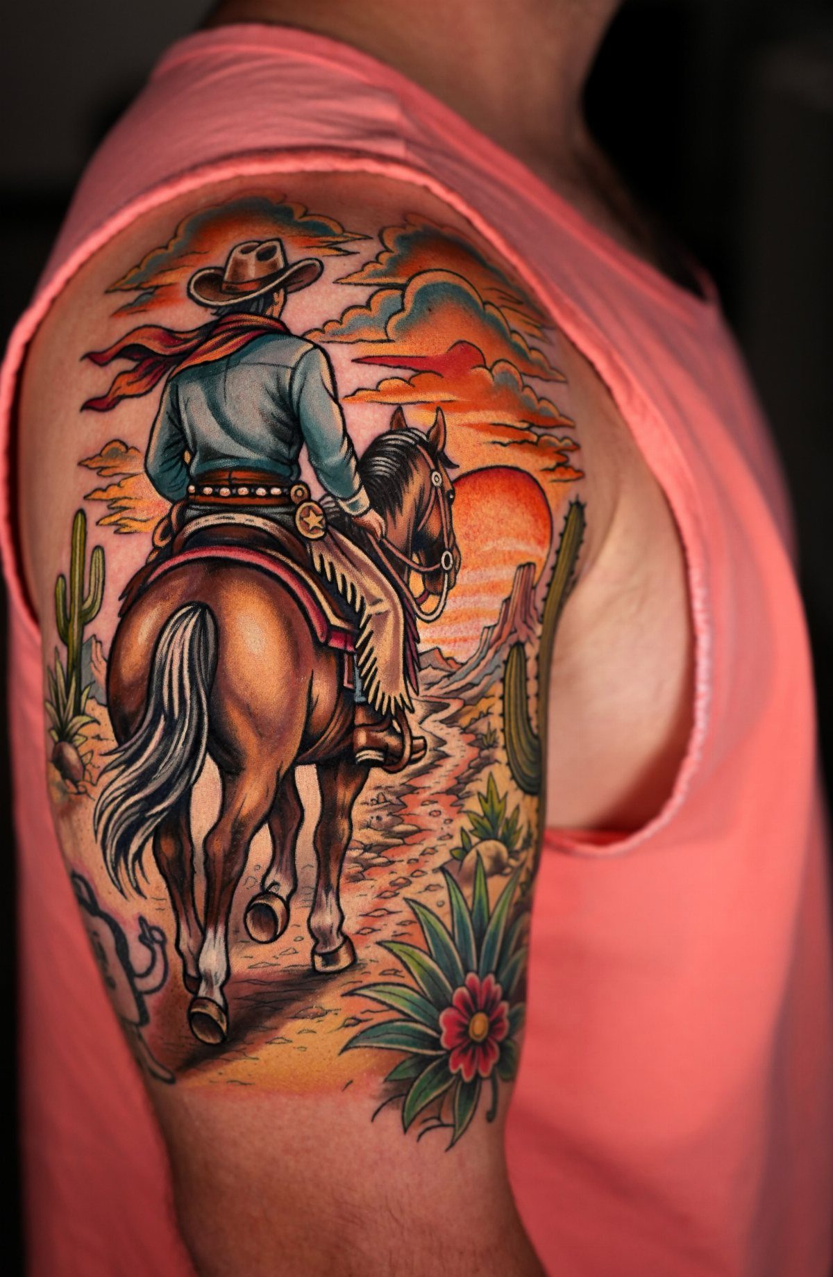 A colorful traditional tattoo of a cowboy riding a horse through a desert landscape.